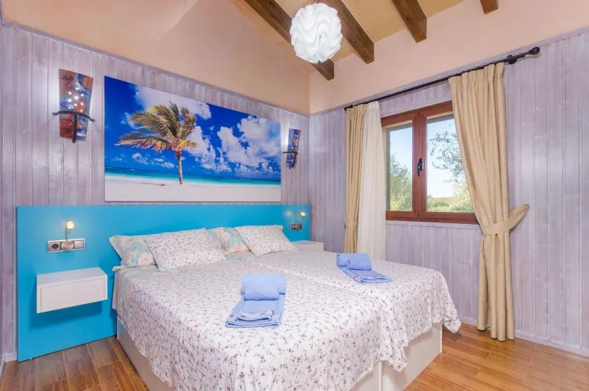 Un dormitorio con una cama doble, un cabecero turquesa y una ventana con cortinas.