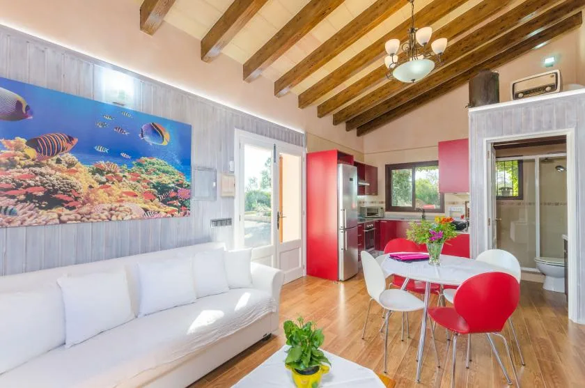 Una luminosa sala de estar y comedor con asientos blancos y una mesa roja.