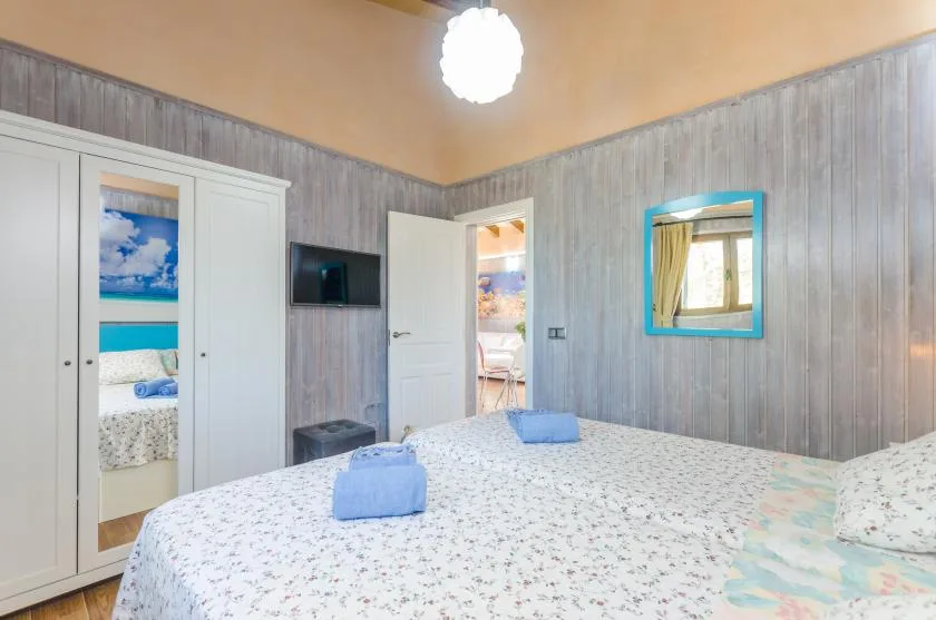 Un dormitorio con una cama grande, un armario blanco y paredes grises revestidas.