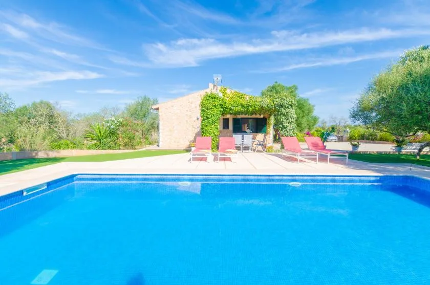 Piscina al aire libre con asientos junto a un edificio de piedra cubierto de enredaderas.