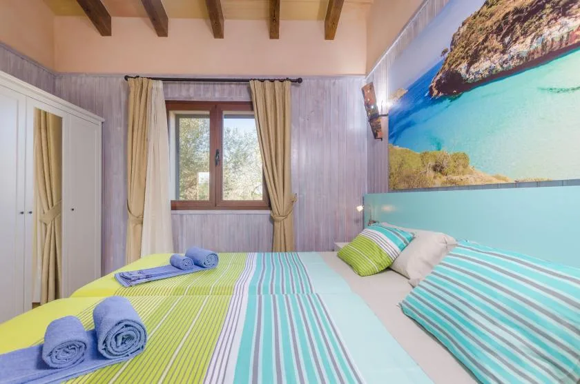 Un dormitorio con ropa de cama a rayas, almohadas y una ventana con cortinas.