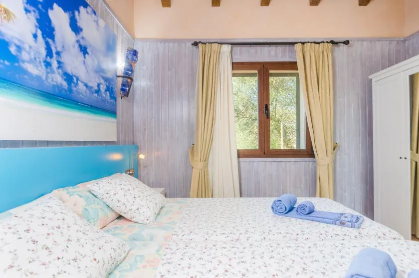 Un dormitorio con una cama, una ventana con cortinas y toallas sobre la ropa de cama.