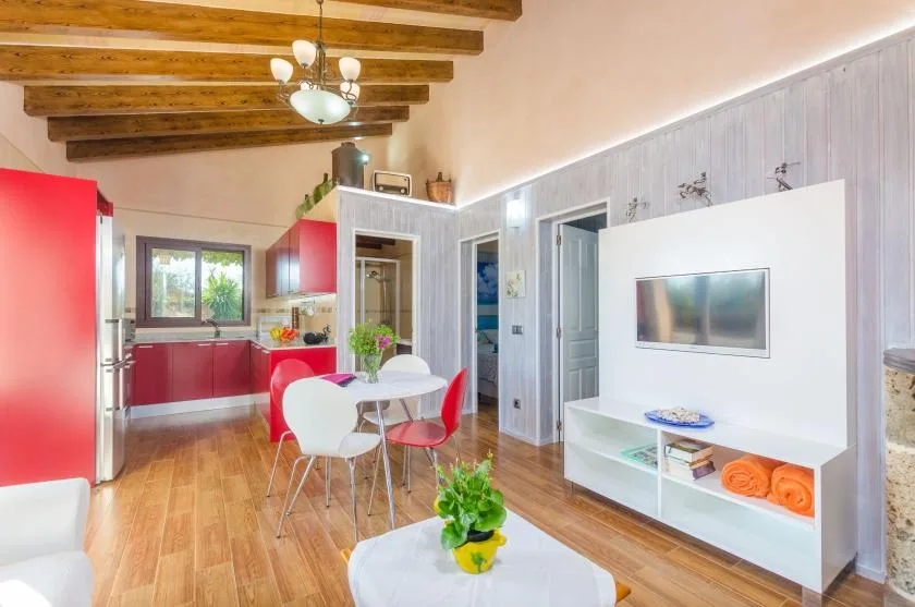 Una luminosa cocina abierta con comedor, mesa y asientos rojos.