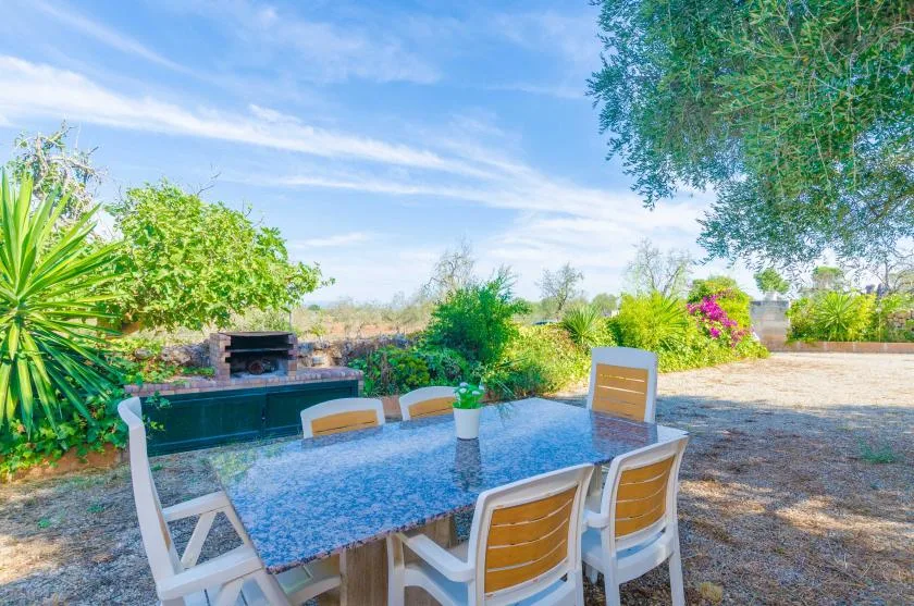 Una zona de comedor al aire libre con mesa y asientos junto a un jardín.