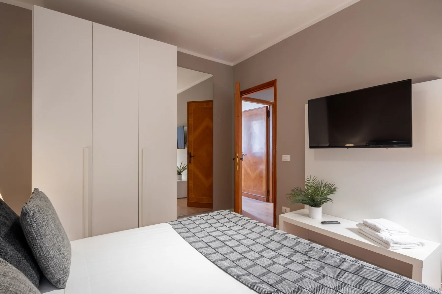 A bedroom with a bed, built-in wardrobes, and a wall-mounted television.