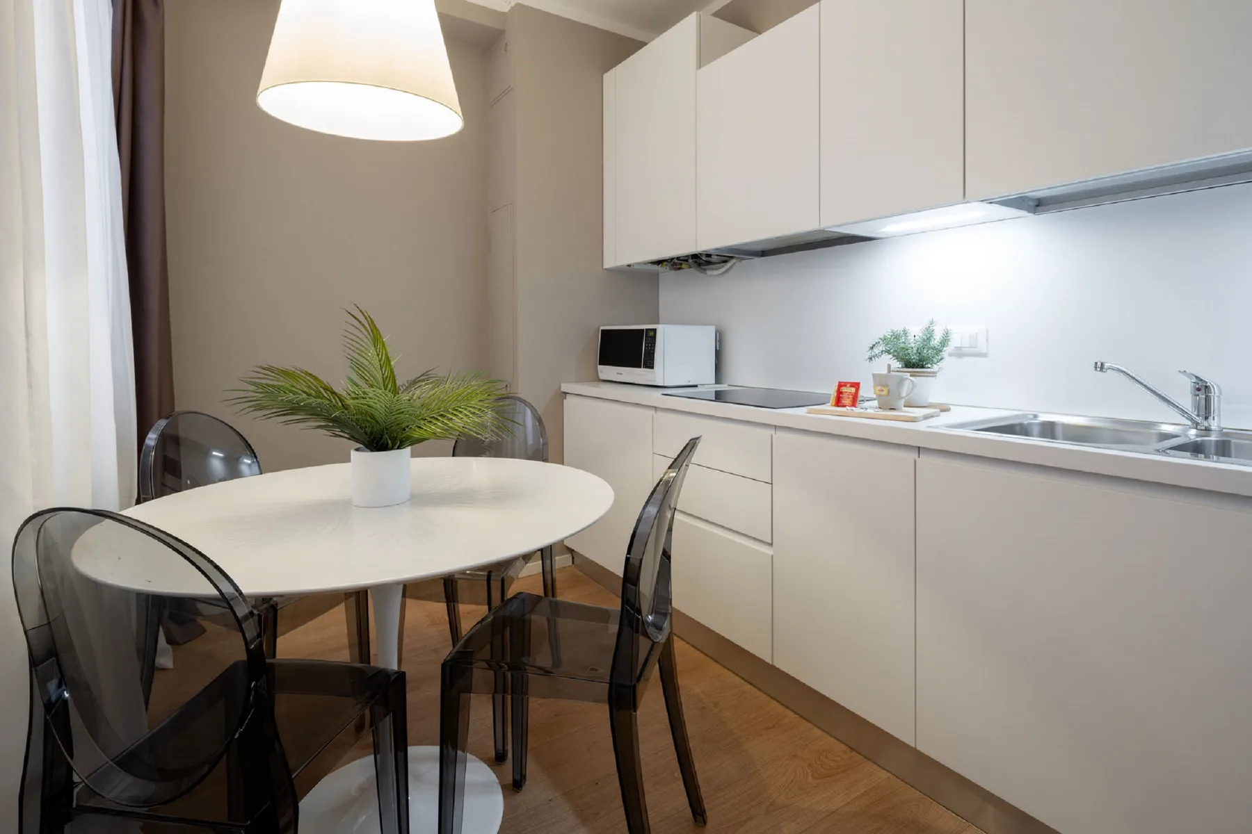 A compact kitchen and dining area with a round table and potted plant.