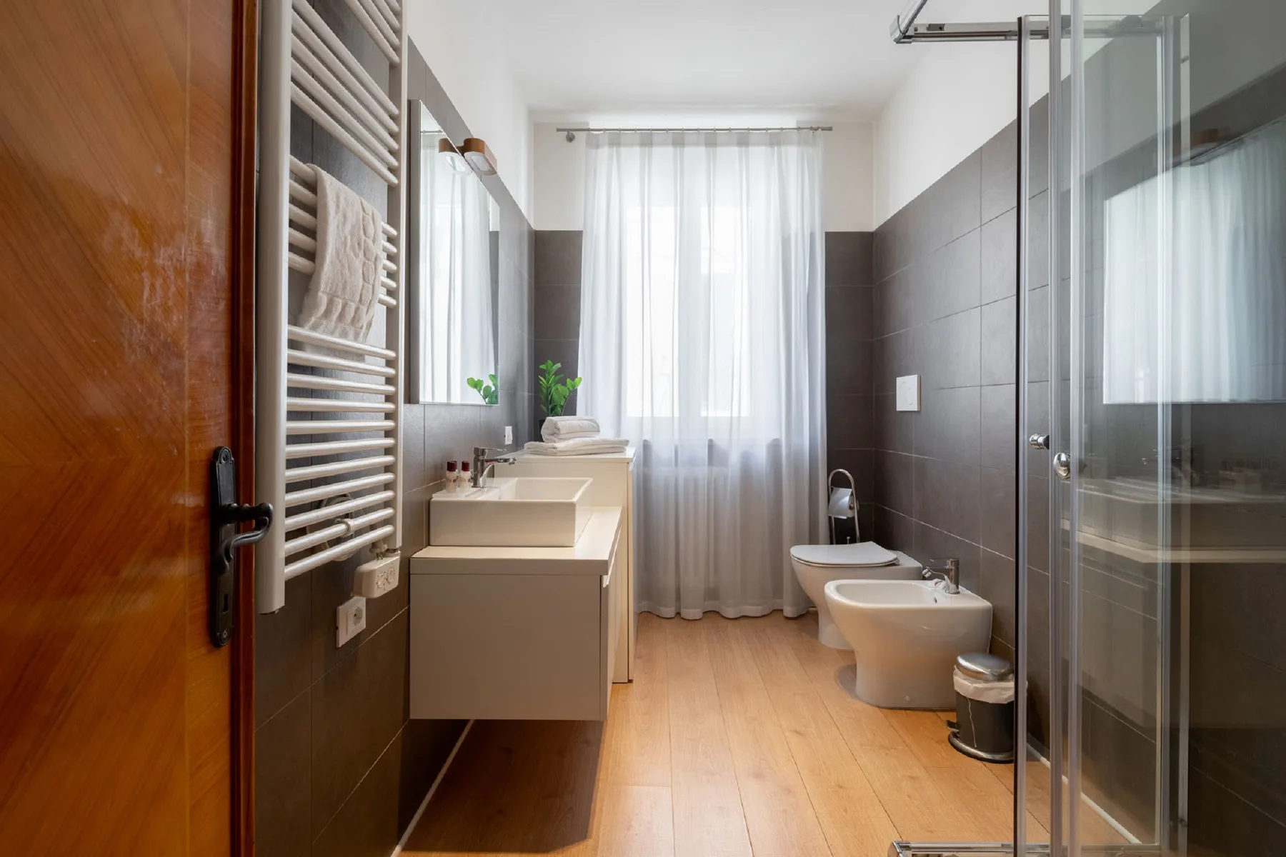 A tiled bathroom with a vanity, toilet, and glass shower enclosure.