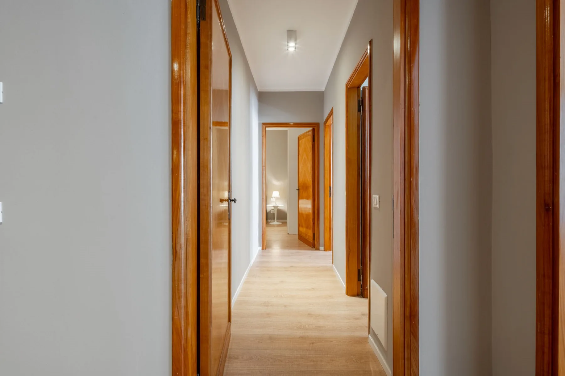A bright hallway with wooden doorways and light flooring.
