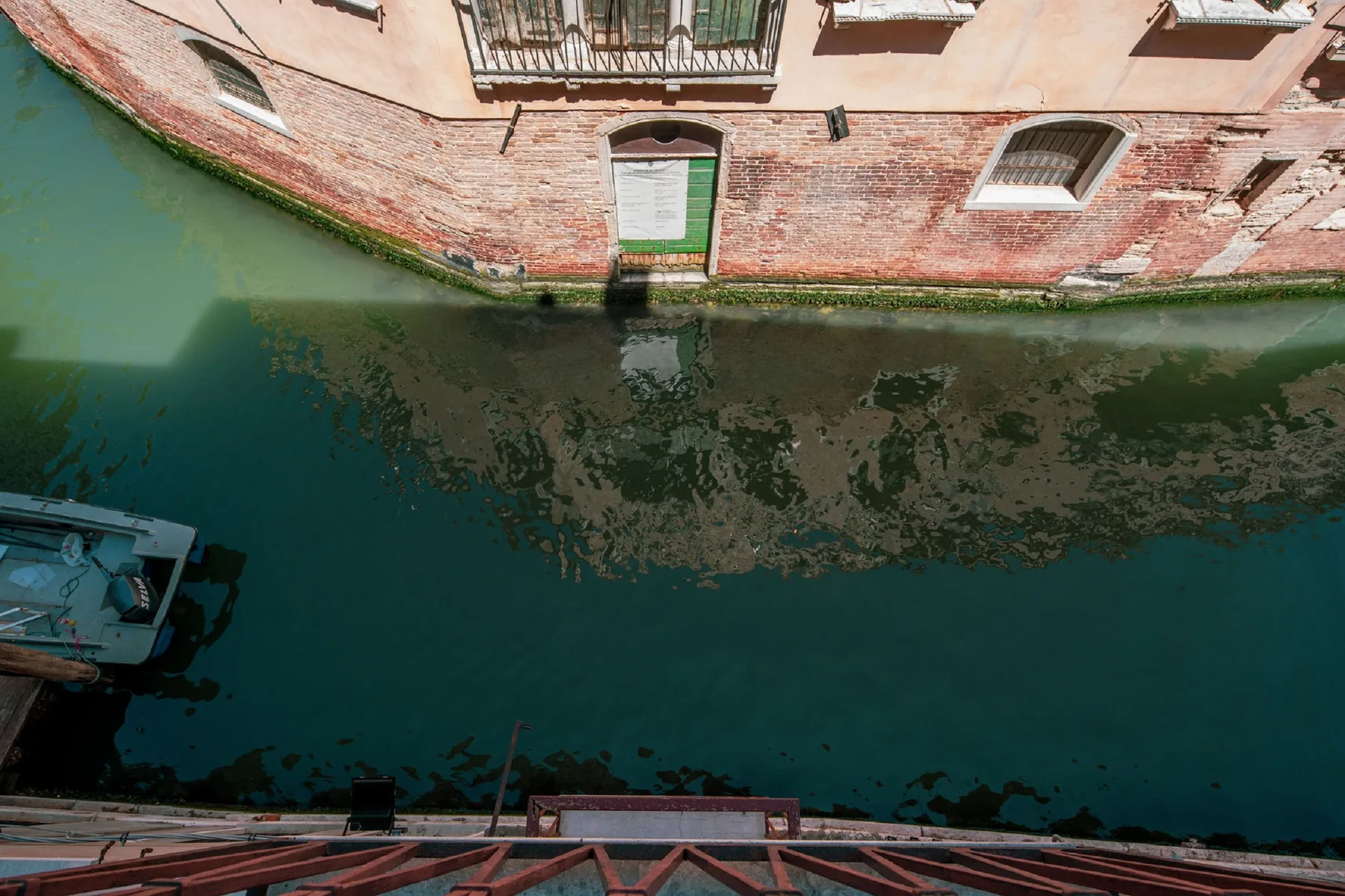 A canal runs beside a brick building with windows and a doorway.