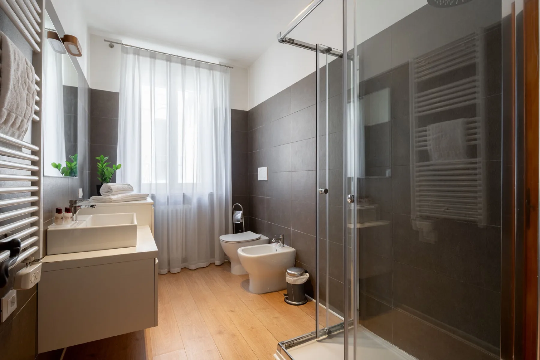 A modern bathroom with a vanity, toilet, and glass-enclosed shower.