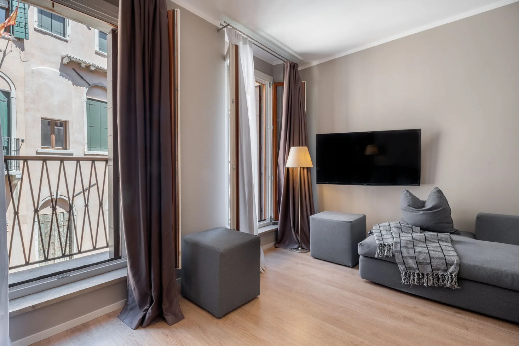 A living room with a gray sofa and a wall-mounted television.