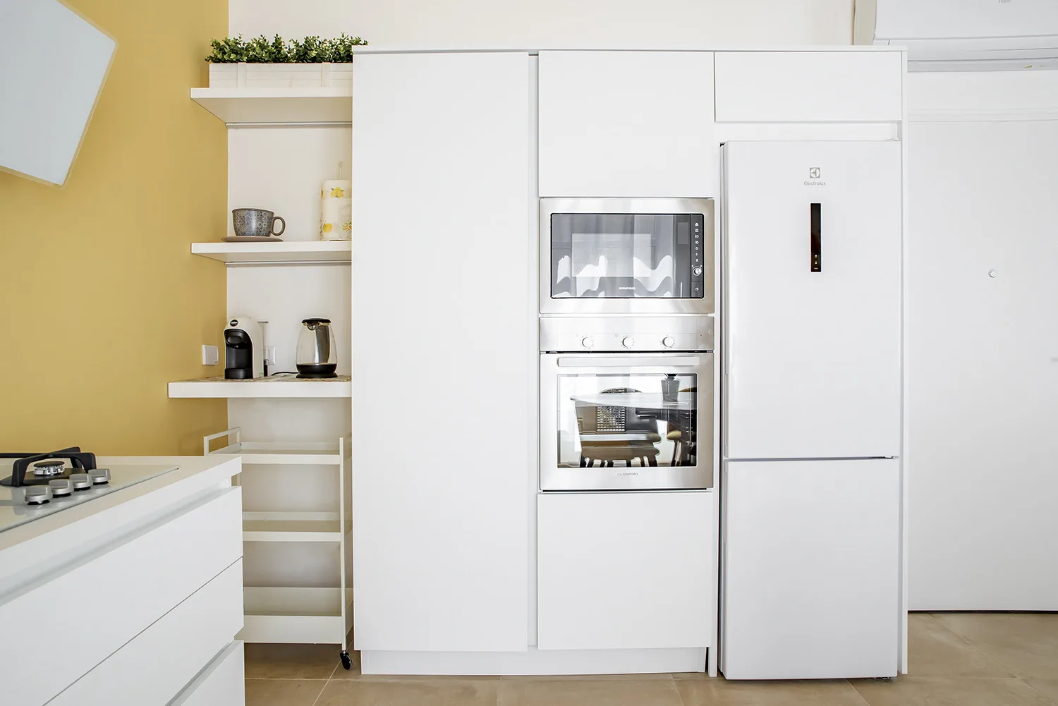 A bright kitchen with built-in appliances and white cabinetry.