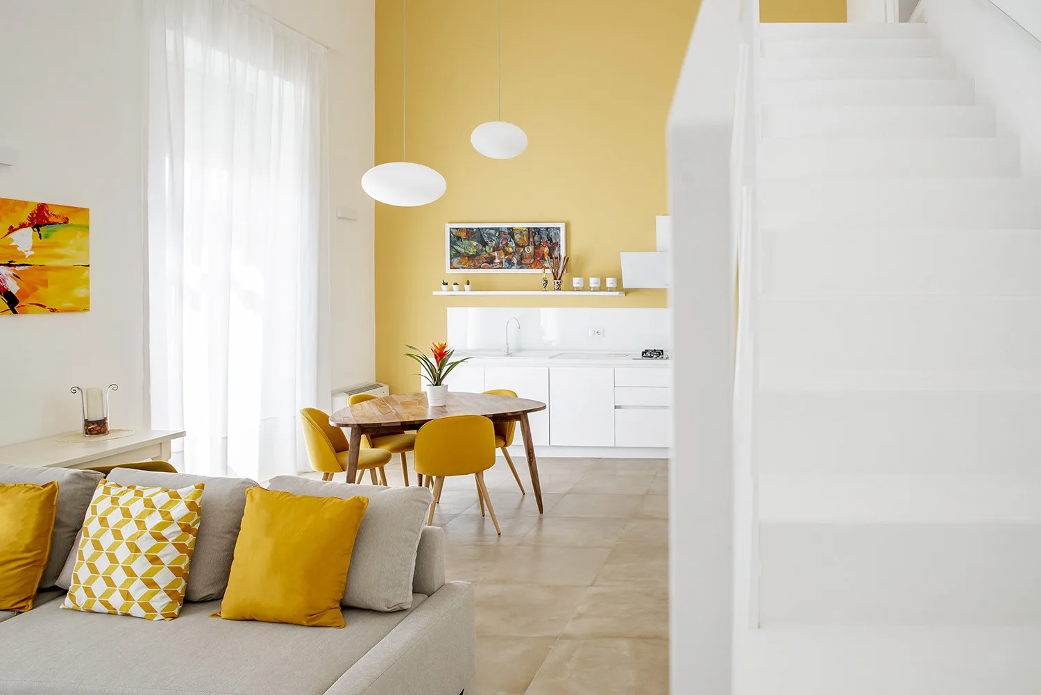 Una luminosa sala-comedor con detalles amarillos y una cocina blanca.