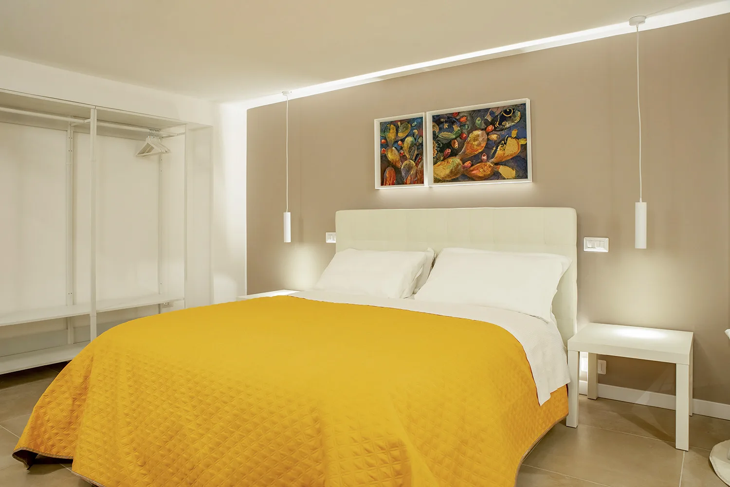 A bedroom with a large bed covered by a yellow bedspread.