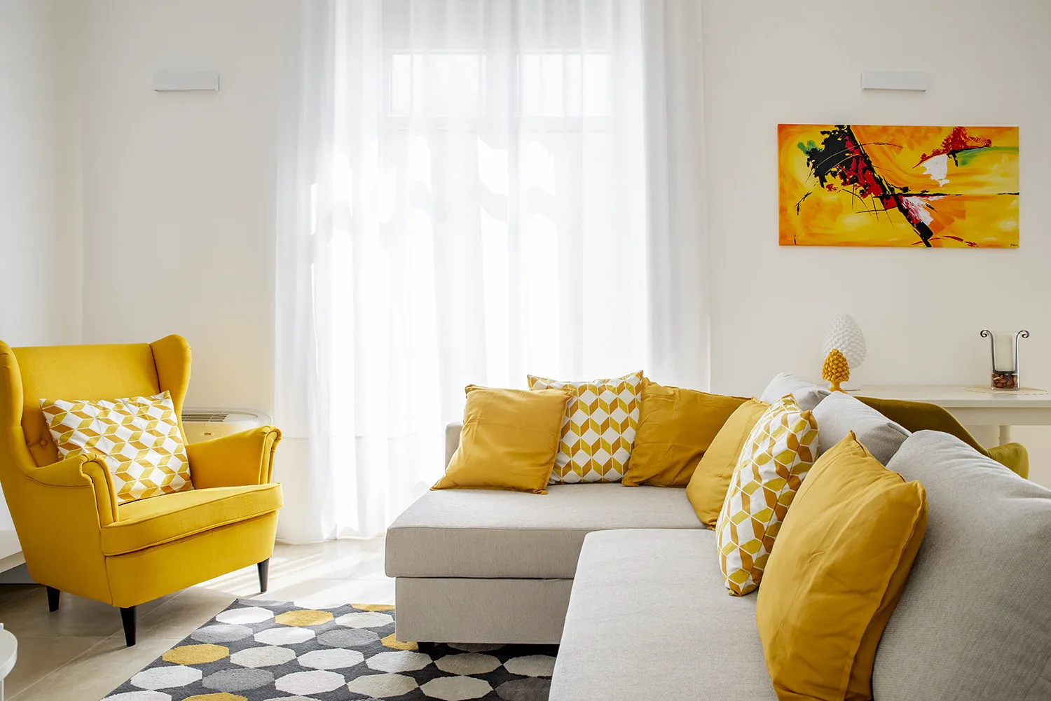 A bright living room with yellow seating and an abstract painting.