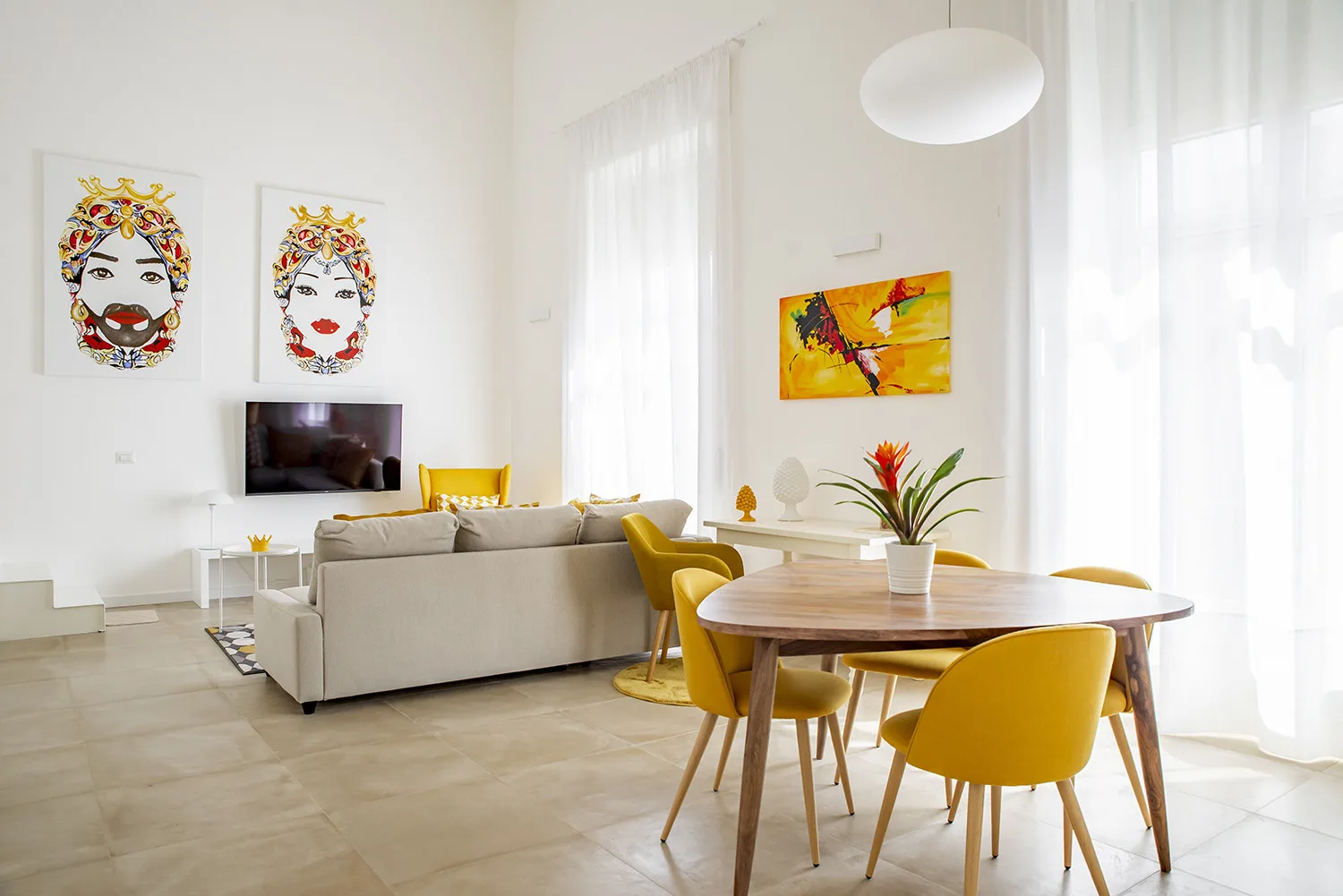 Una luminosa sala de estar y comedor con asientos, una mesa y arte colorido en las paredes.
