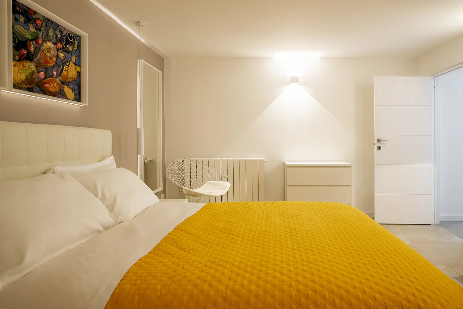A bedroom with a bed covered by a yellow bedspread.
