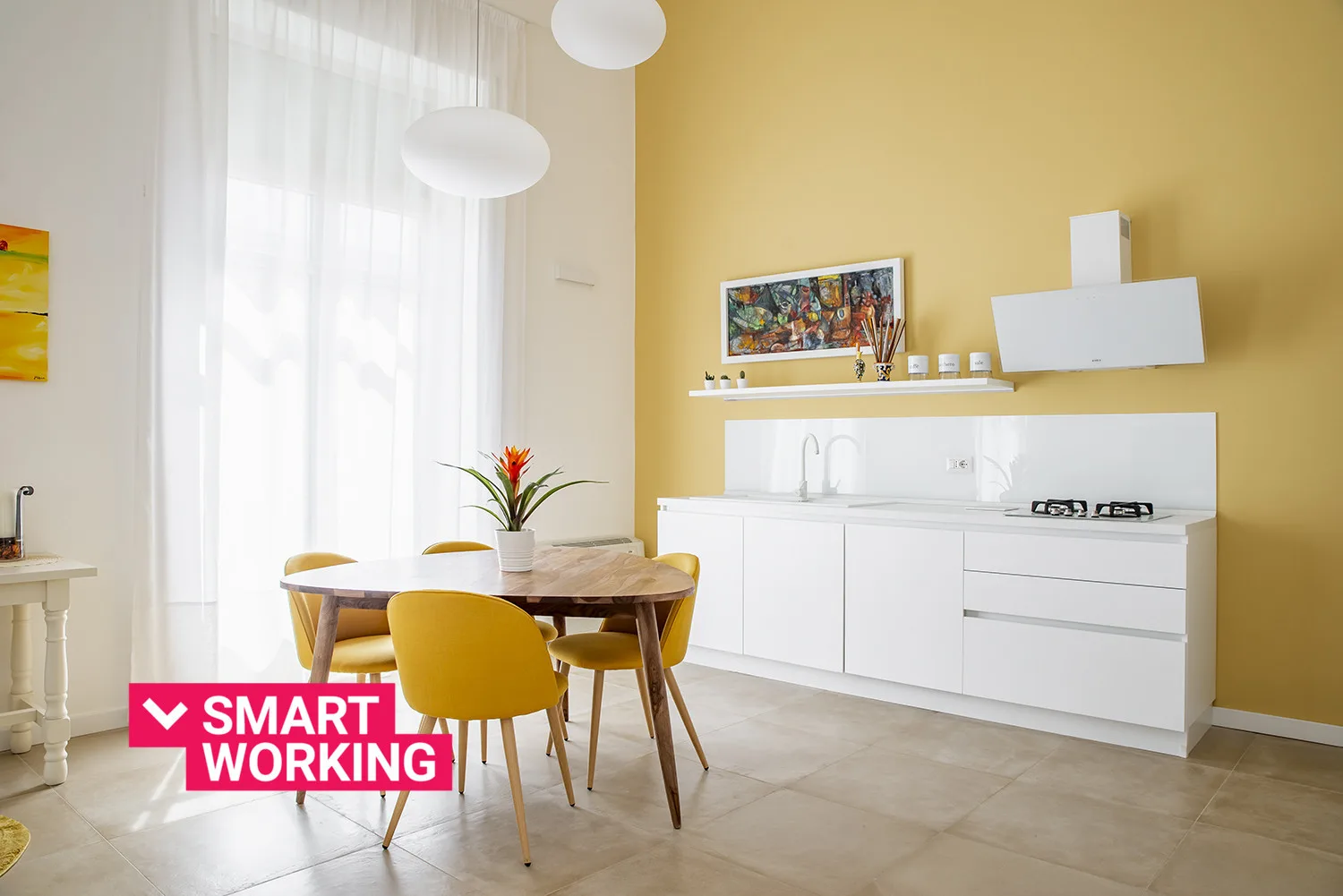 A bright kitchen and dining area with white cabinets and a table beside the window.