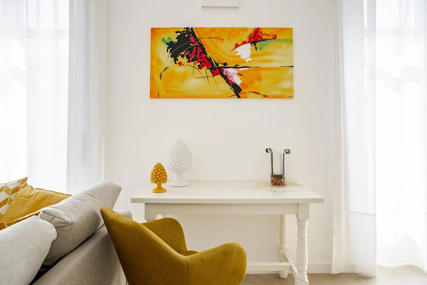 A bright living room with seating and an abstract painting above a console table.