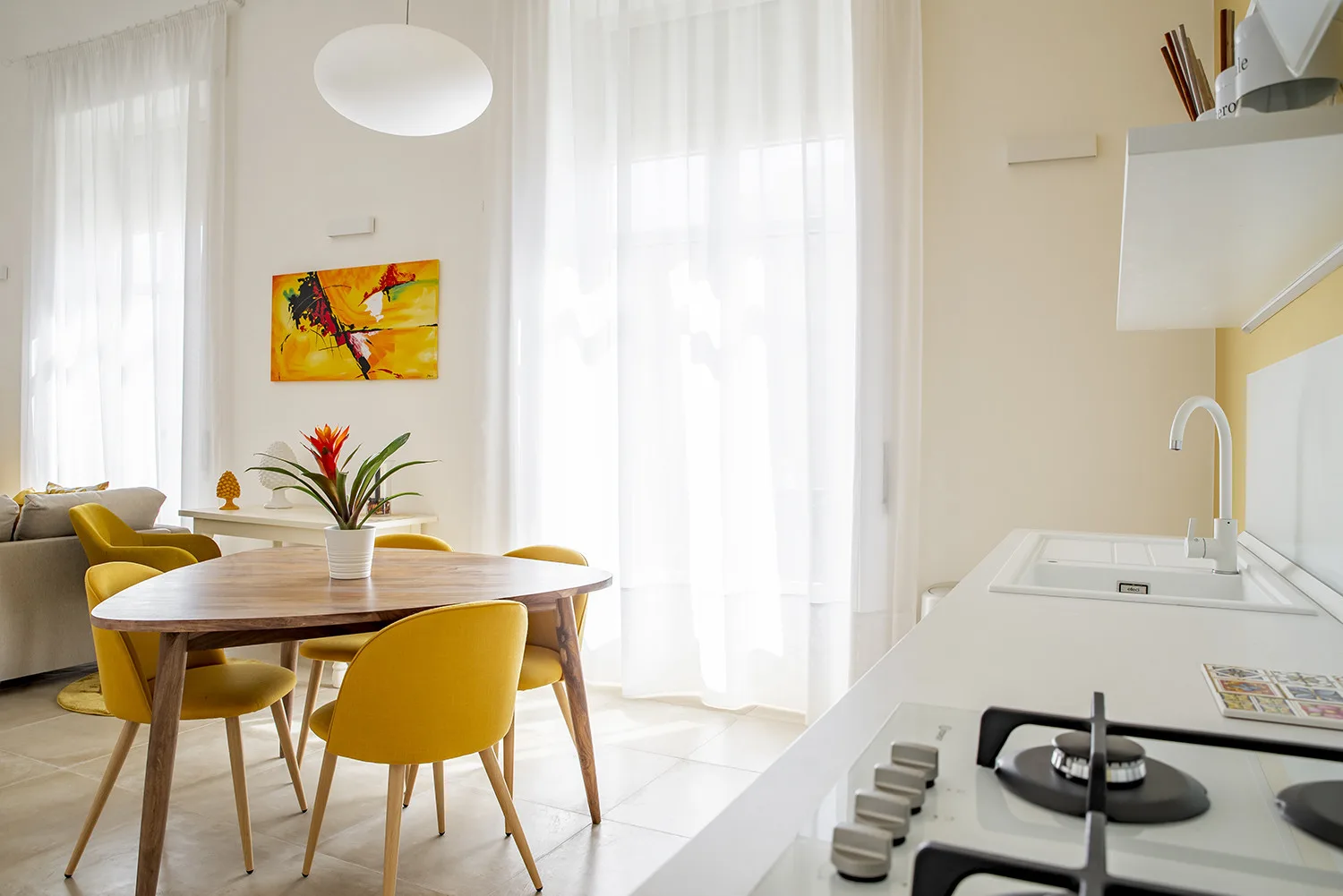 Un comedor luminoso con asientos amarillos junto a la cocina.