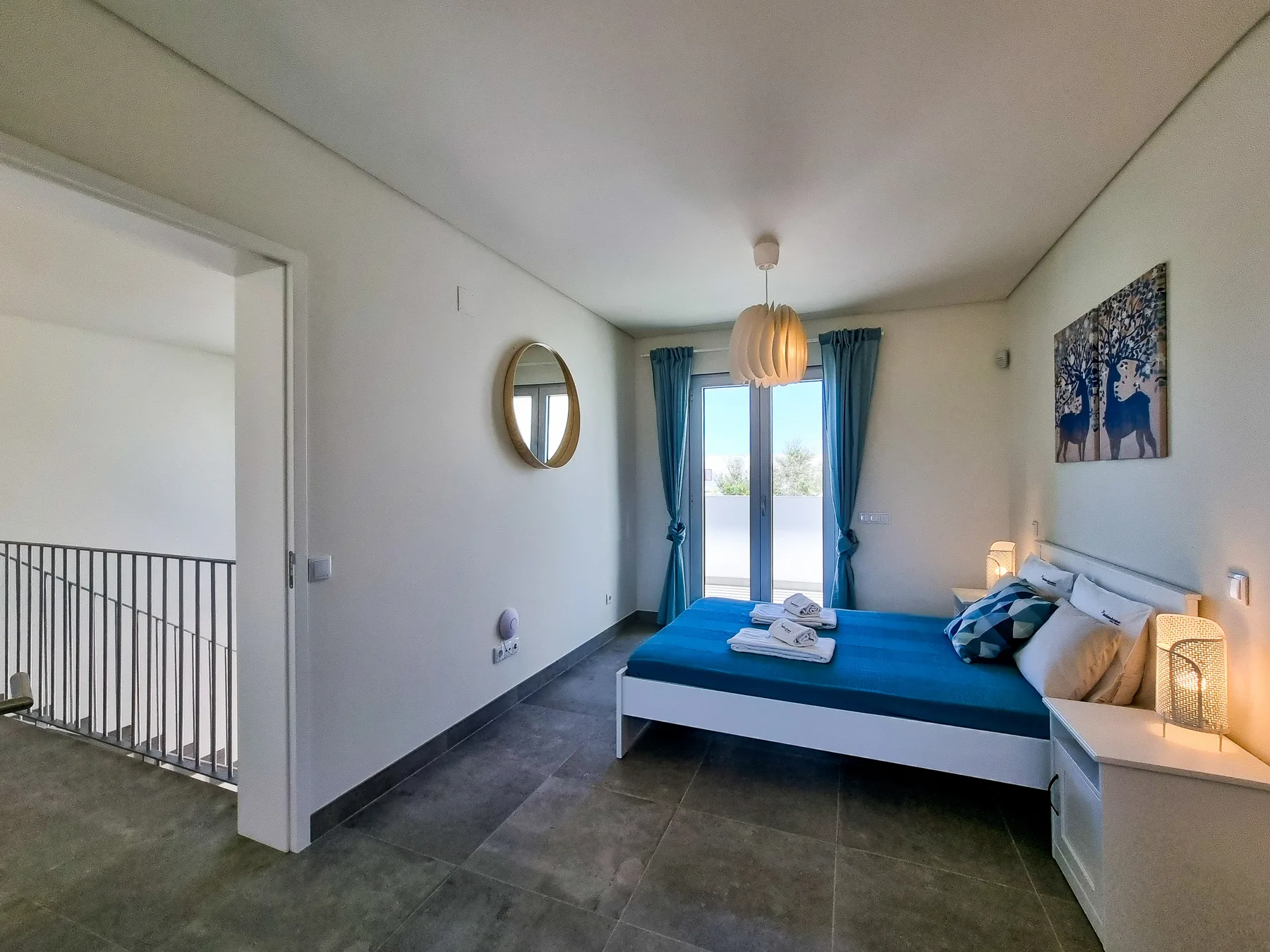 Un dormitorio con una cama junto a puertas de cristal que dan a un balcón.