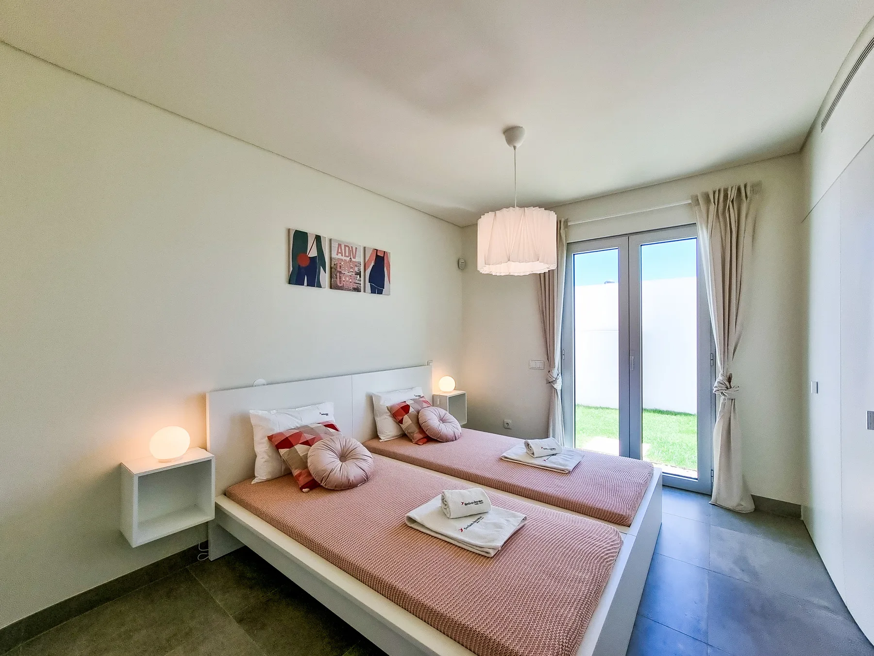 Un dormitorio luminoso con dos camas junto a una puerta de cristal.