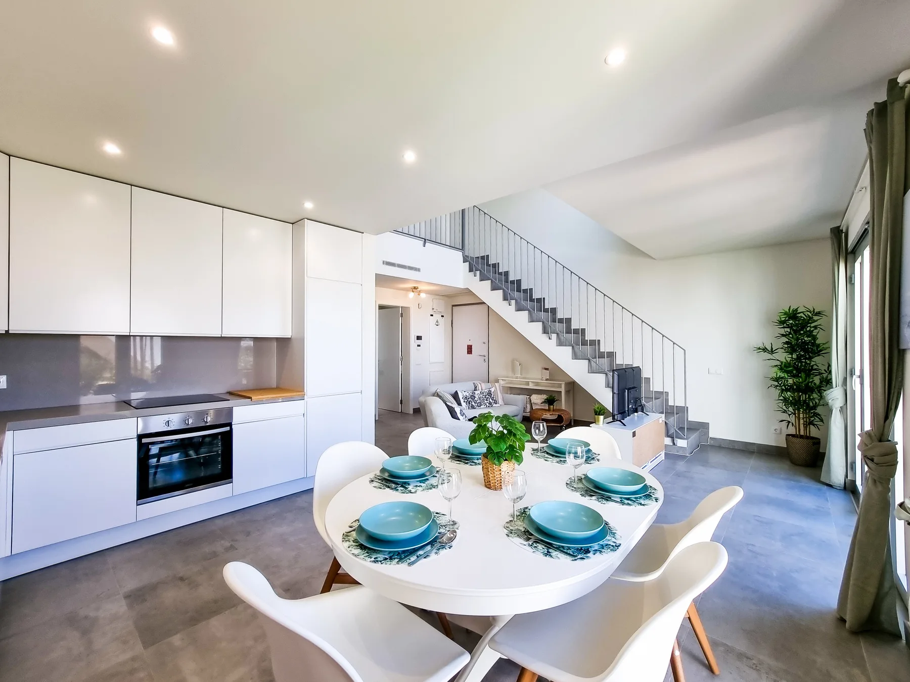 Una luminosa cocina-comedor abierta con una escalera y una mesa preparada para comer.