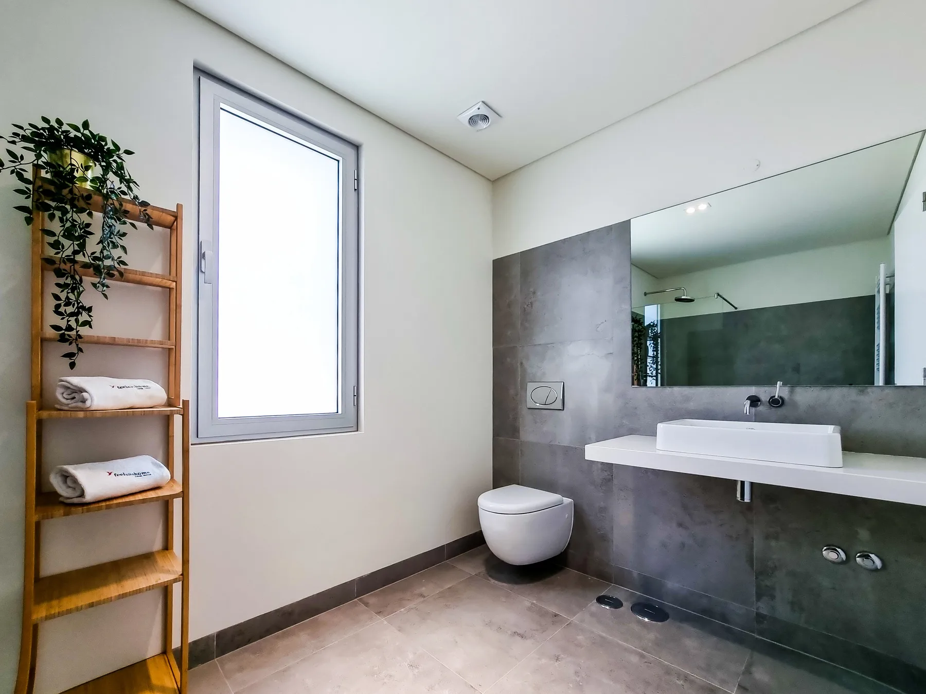 Un baño moderno con lavabo suspendido, espejo e inodoro.