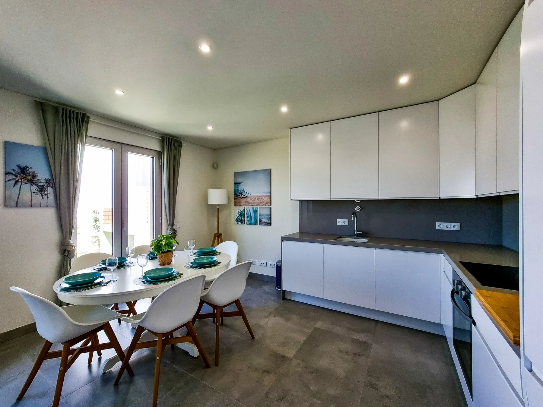 Una cocina y comedor luminosos con una mesa preparada junto a grandes ventanas.