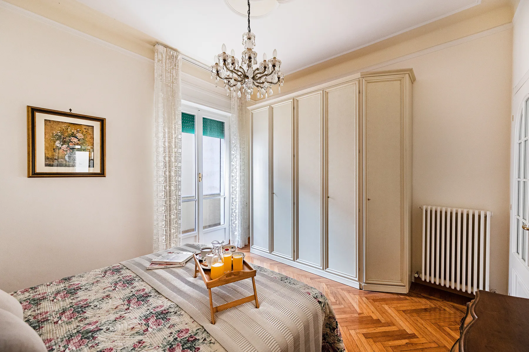 A bedroom with a bed, wardrobe, and small table by the window.