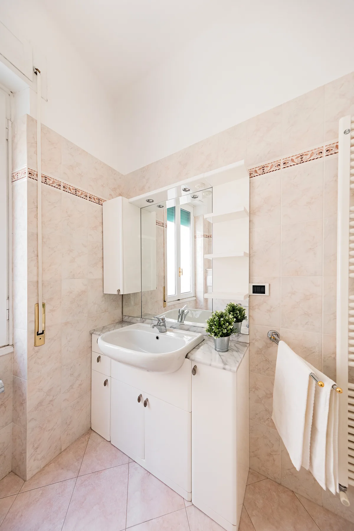 A tiled bathroom with a vanity, mirrored cabinet, and towel warmer.