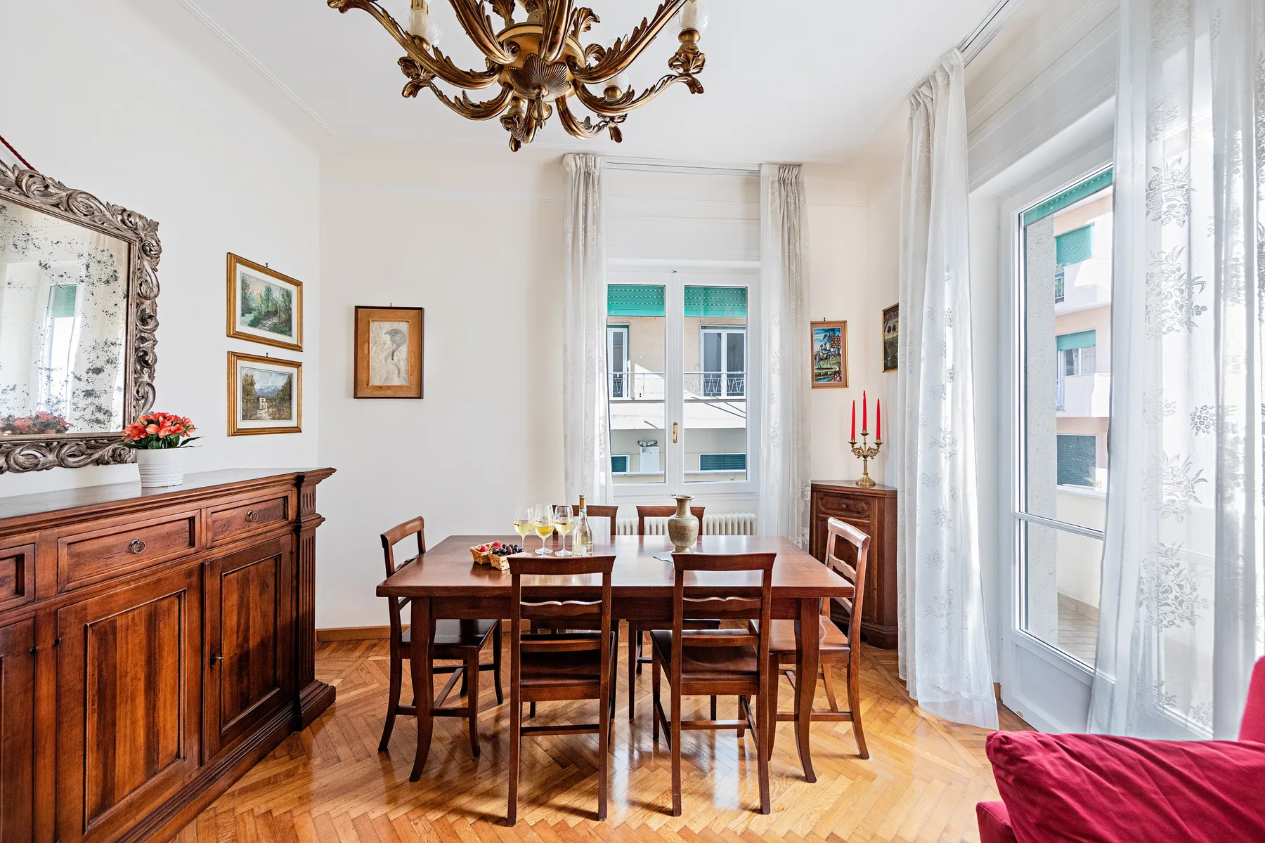 A bright dining room with a wooden table and chairs beside tall windows.