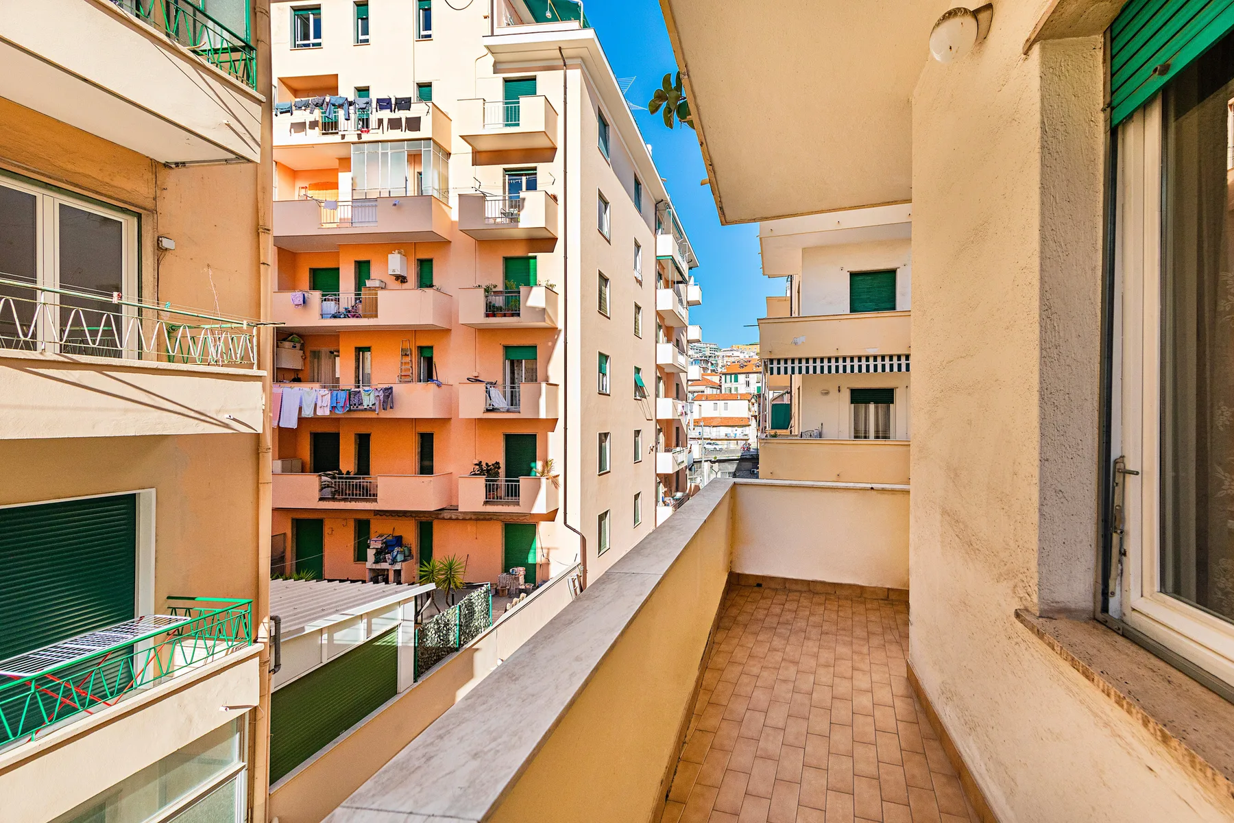 A narrow balcony overlooks neighboring apartment buildings and their balconies.