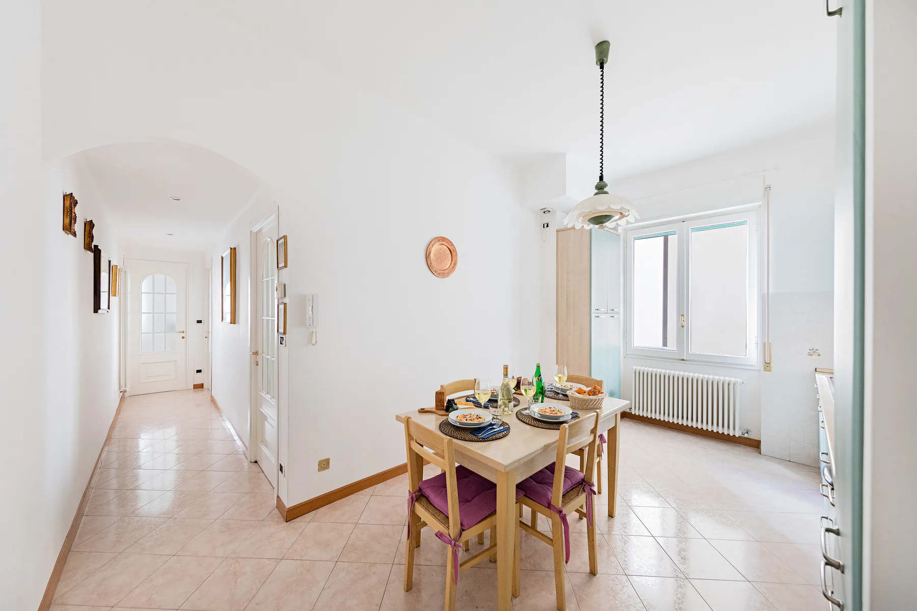 A bright dining area with a wooden table and chairs beside a window.