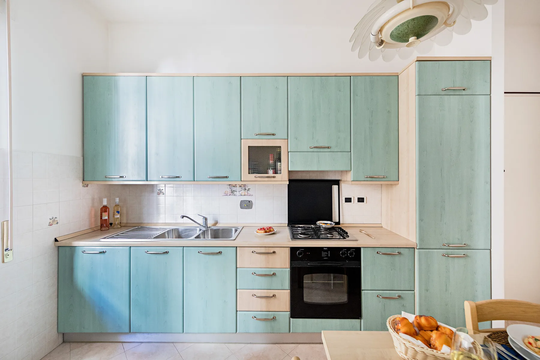 A kitchen with pale blue cabinets, a countertop, and a built-in oven.