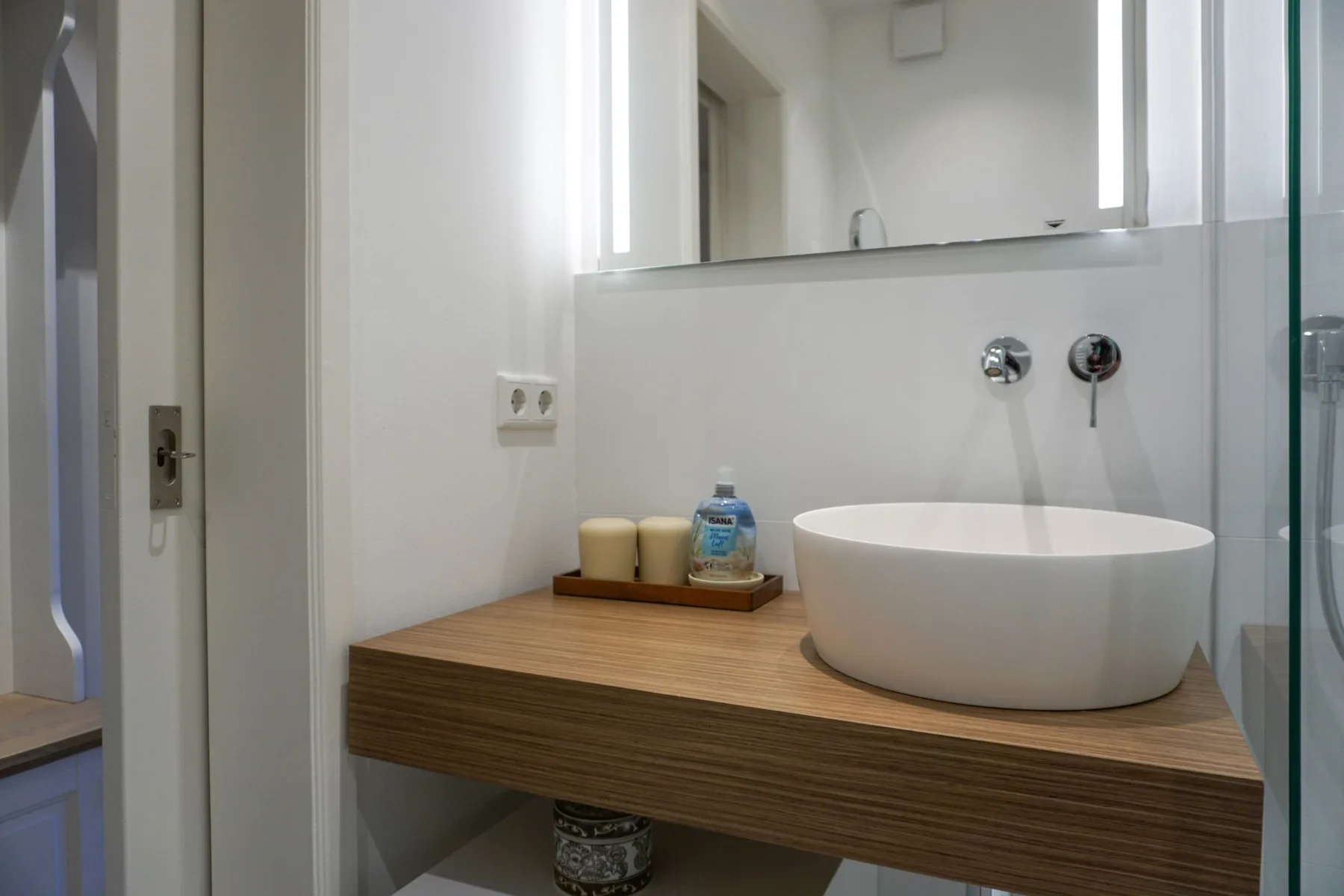 Un lavabo de baño con un cuenco blanco sobre la encimera, bajo un espejo.