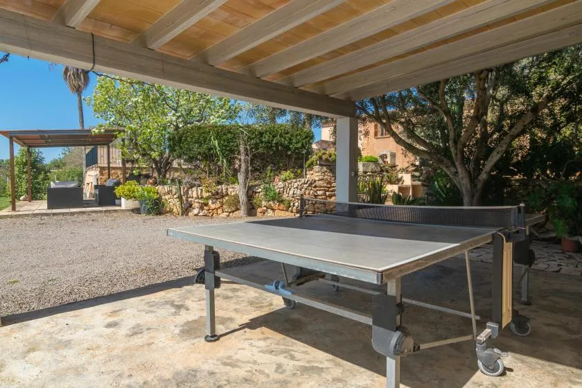 A shaded outdoor area with a ping-pong table beneath a covered patio.