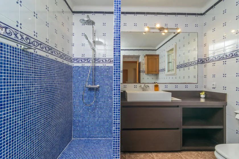 A tiled bathroom with a glass shower, sink, and large mirror.