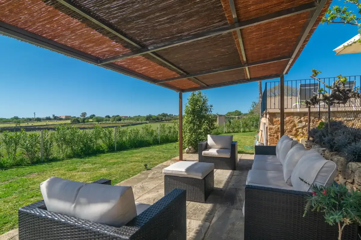 A covered outdoor seating area overlooks a green field.