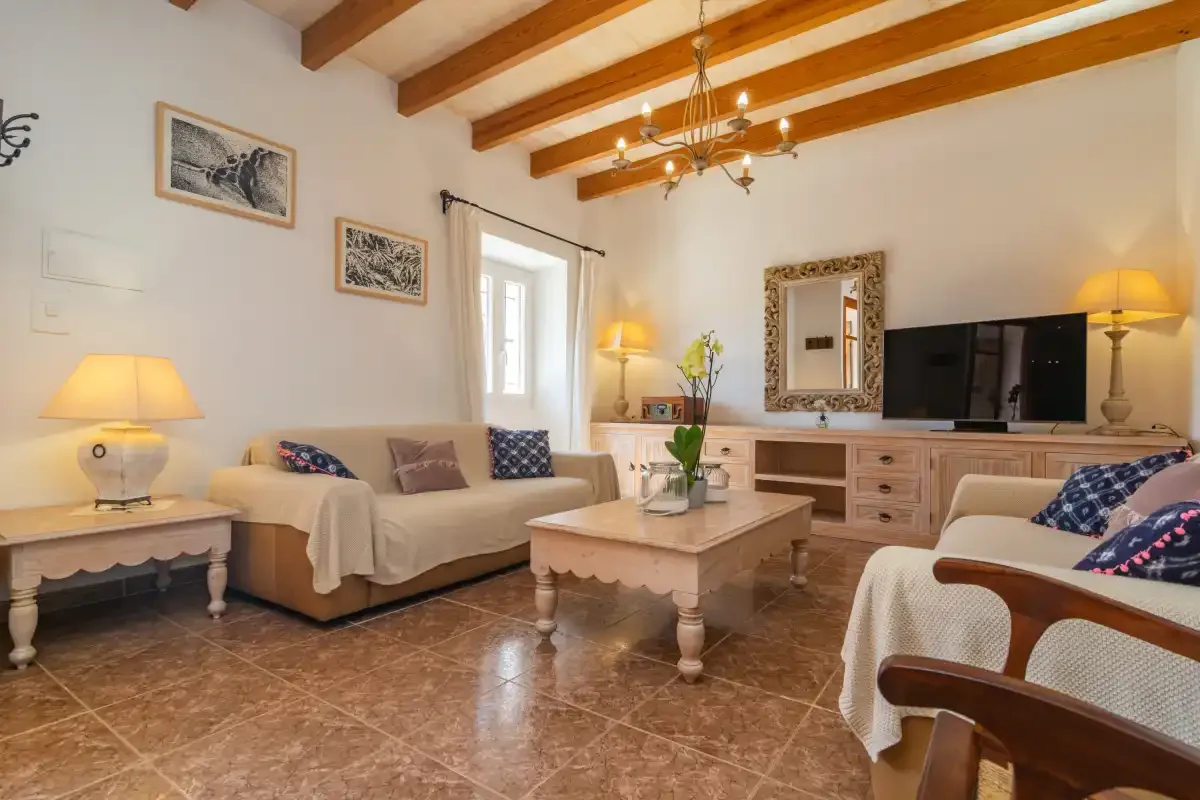A bright living room with seating, a coffee table, and a television.