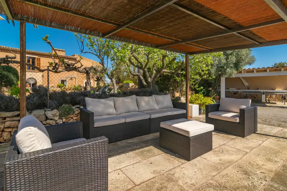 A shaded outdoor seating area with cushioned furniture and a stone patio.