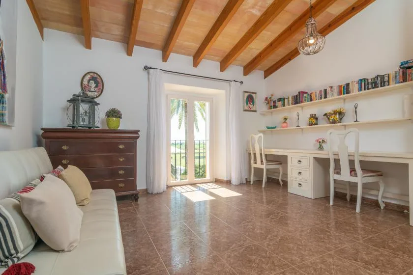 A bright room with a long desk, seating, and glass doors opening to a balcony.