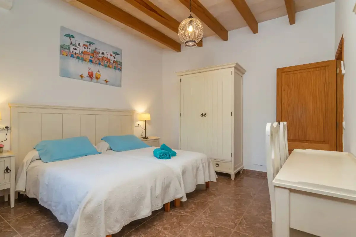 A bedroom with a double bed, wardrobe, and wooden ceiling beams.