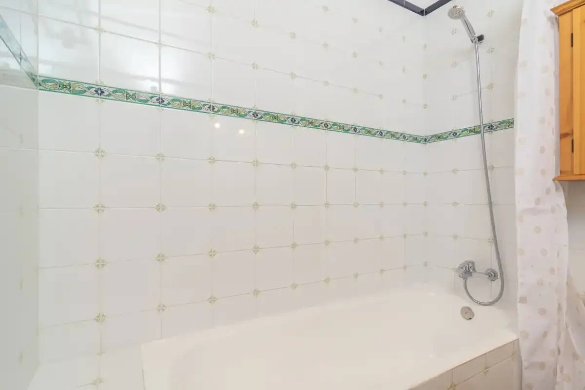 A tiled bathroom with a bathtub and wall-mounted shower.