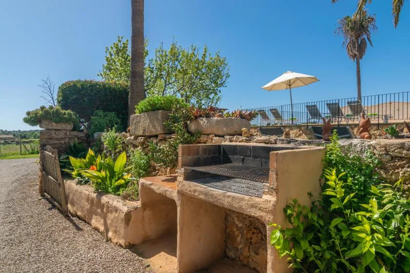 A landscaped outdoor patio features a built-in grill and an open umbrella.