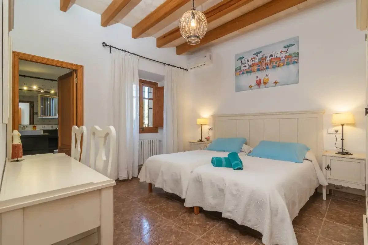 A bedroom with two beds, bedside tables, and exposed ceiling beams.