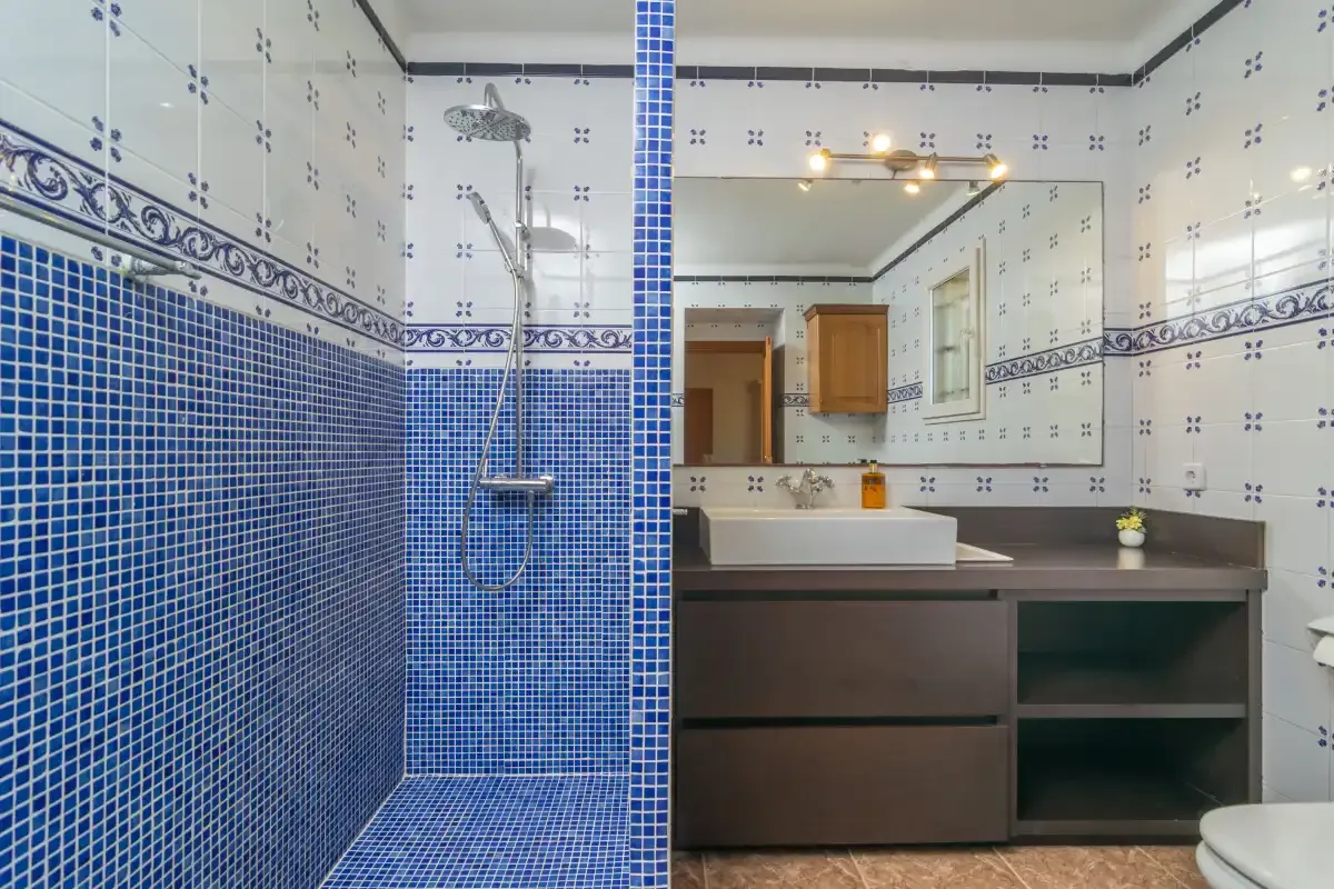 A tiled bathroom with a shower and a wide vanity beneath a mirror.
