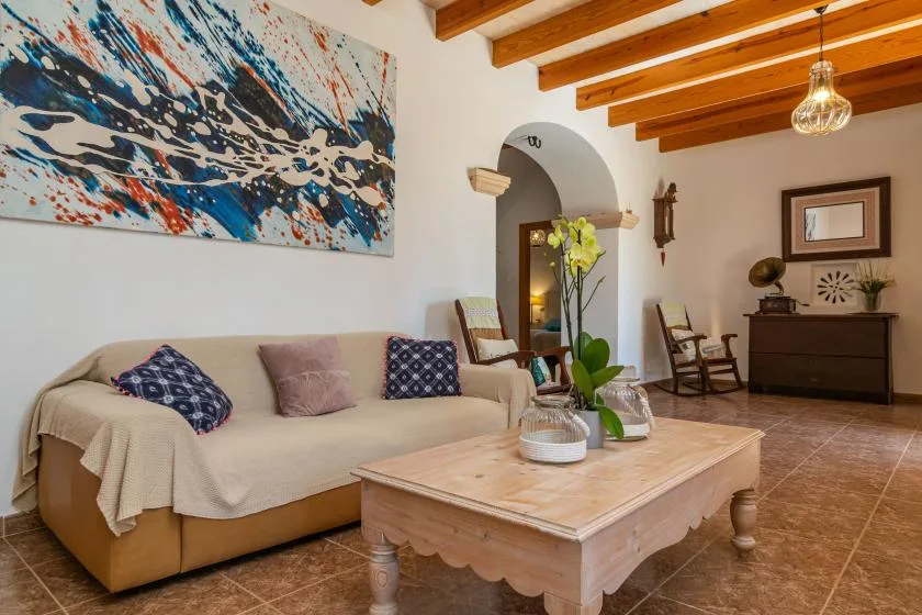 A living room with a sofa, a wooden coffee table, and colorful wall art.