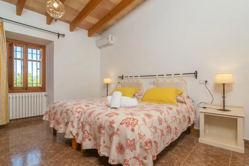A bedroom with a double bed, floral bedding, and exposed wooden ceiling beams.