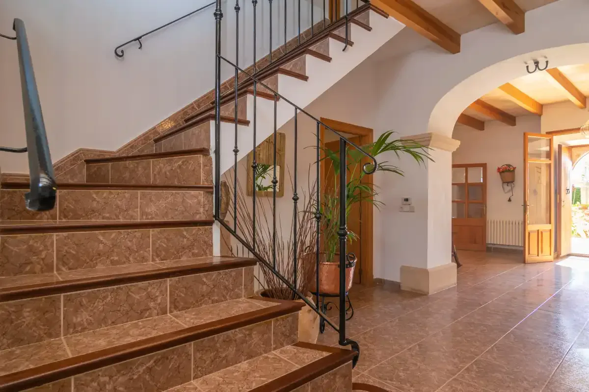 An interior entry hall with a tiled staircase and an arched opening.
